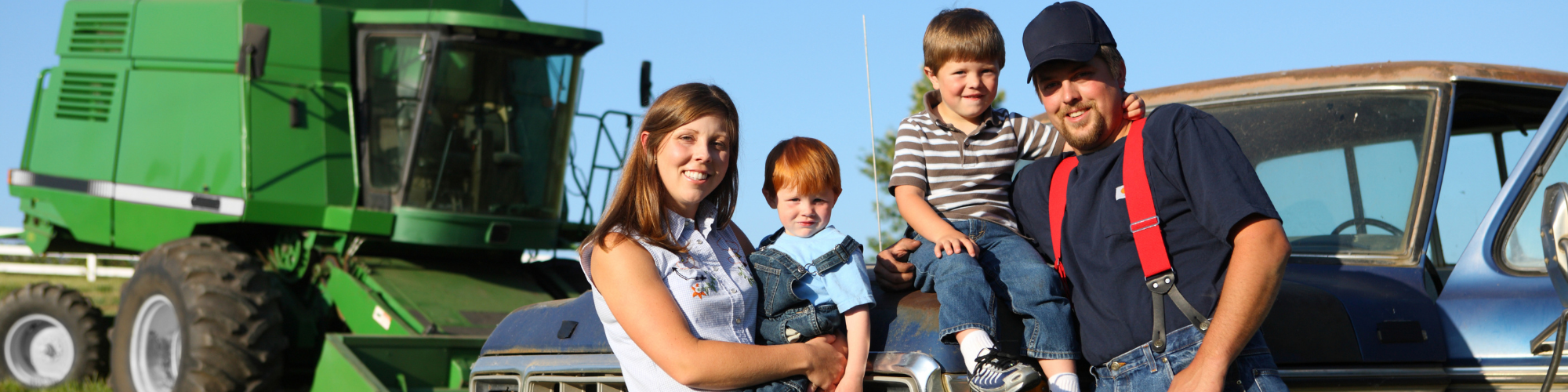 family posing in front of a farm truck and tractor 